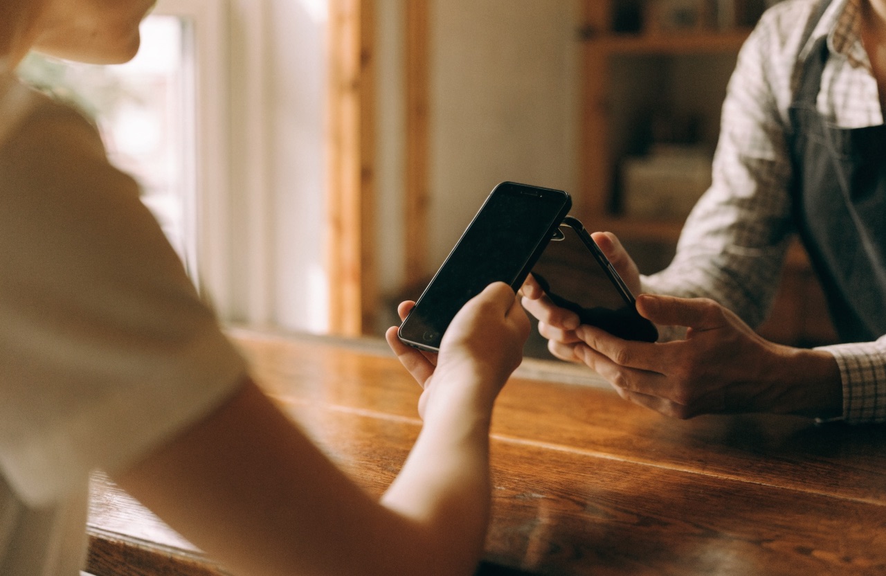 A shopkeeper scanning a customer's phone across a wooden counter
